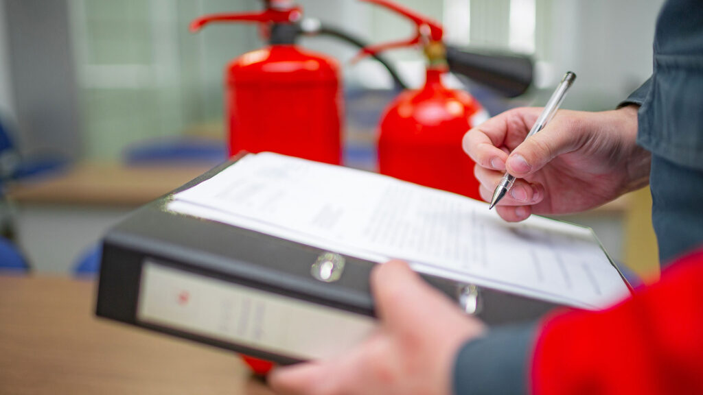 a person signing a document with fire extinguisher in background