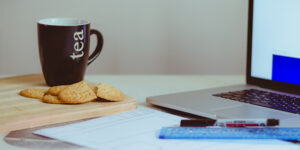 cup wit hbiscuits and a laptop screen